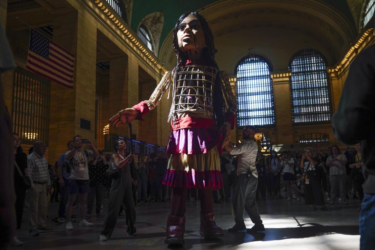 Puppeteers "walk" a large puppet named Little Amal in New York's Grand Central Station.
