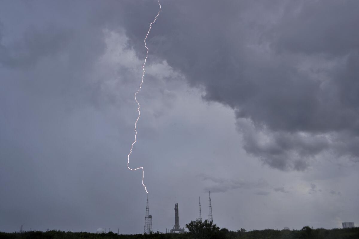 A lightning bolt strikes a tower near NASA's new moon rocket on Launch Pad 39-B in Cape Canaveral, Fla., on Saturday, Aug. 27, 2022. NASA will try again Saturday, Sept. 3, 2022, to launch the first flight of its 21st-century moon-exploration program, named Artemis, Apollo's mythological twin sister, after engine trouble halted the first countdown. (AP Photo/Chris O'Meara)