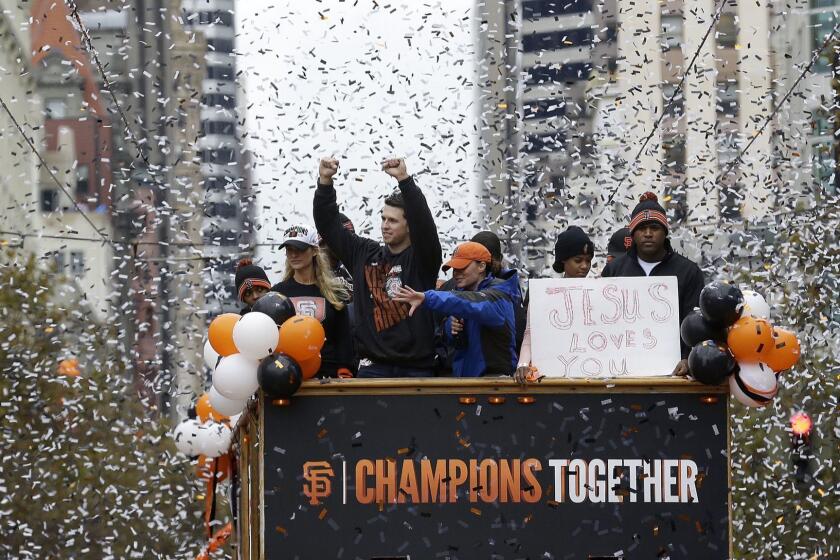 San Francisco Giants catcher Buster Posey, top, left, waves to fans as he rides with pitcher Santiago Casilla, right, during the baseball team's 2014 World Series victory parade in San Francisco, Friday, Oct. 31, 2014. (AP Photo/Jeff Chiu) ** Usable by LA, DC, CGT and CCT Only **