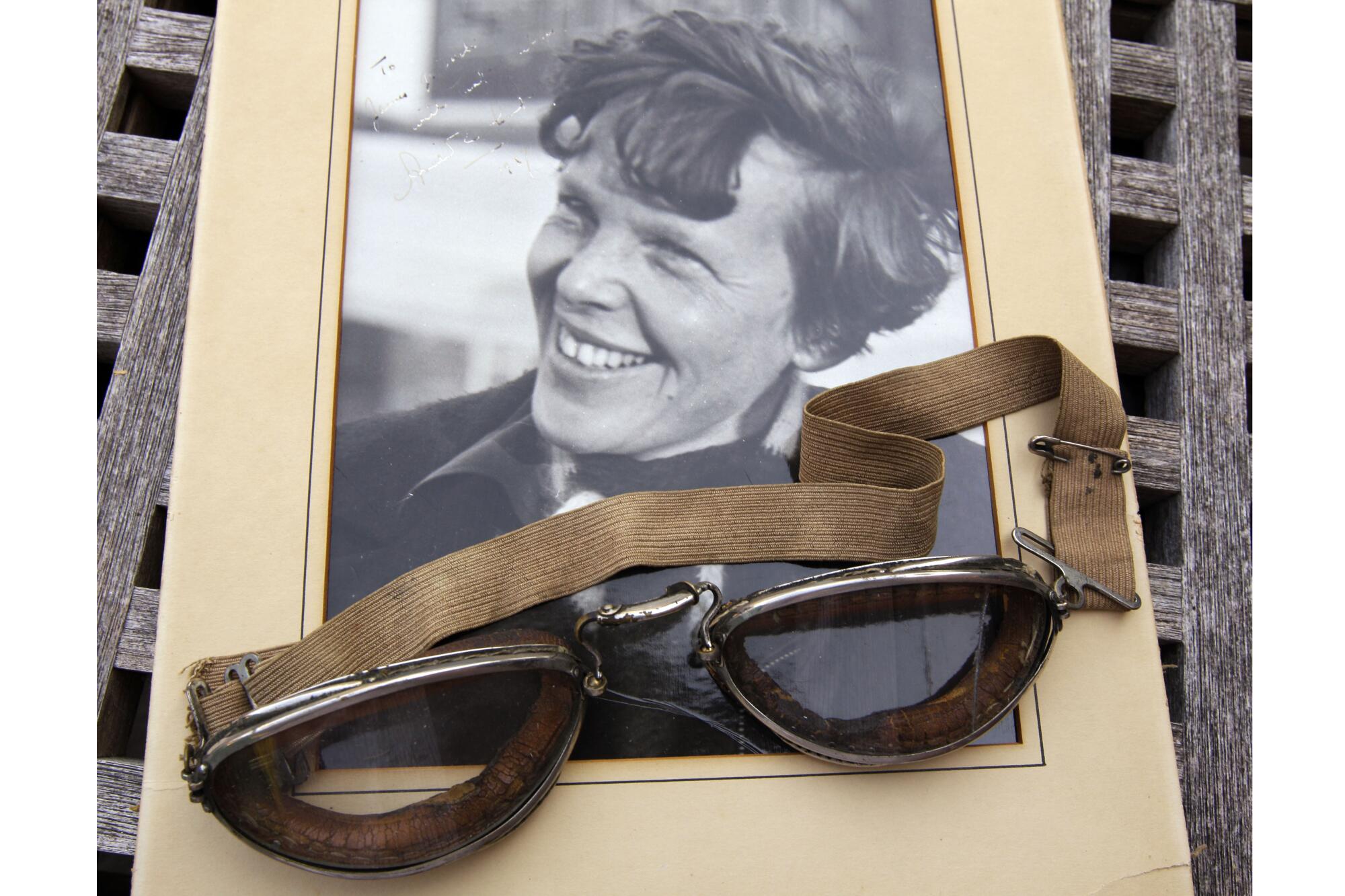 An original, unpublished personal photo of Amelia Earhart dated 1937, along with goggles 