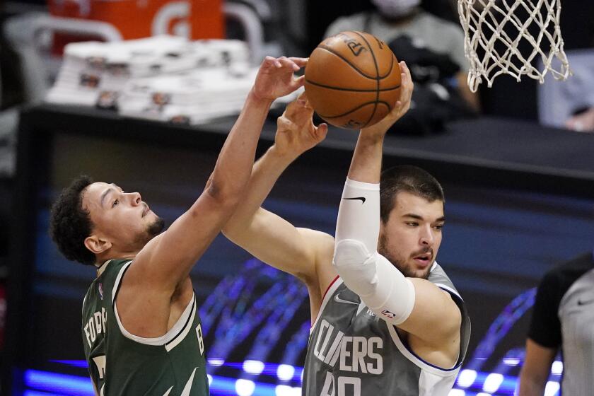 Milwaukee Bucks guard Bryn Forbes, left, knocks the ball from the hands of Los Angeles Clippers center Ivica Zubac during the first half of an NBA basketball game Monday, March 29, 2021, in Los Angeles. (AP Photo/Mark J. Terrill)