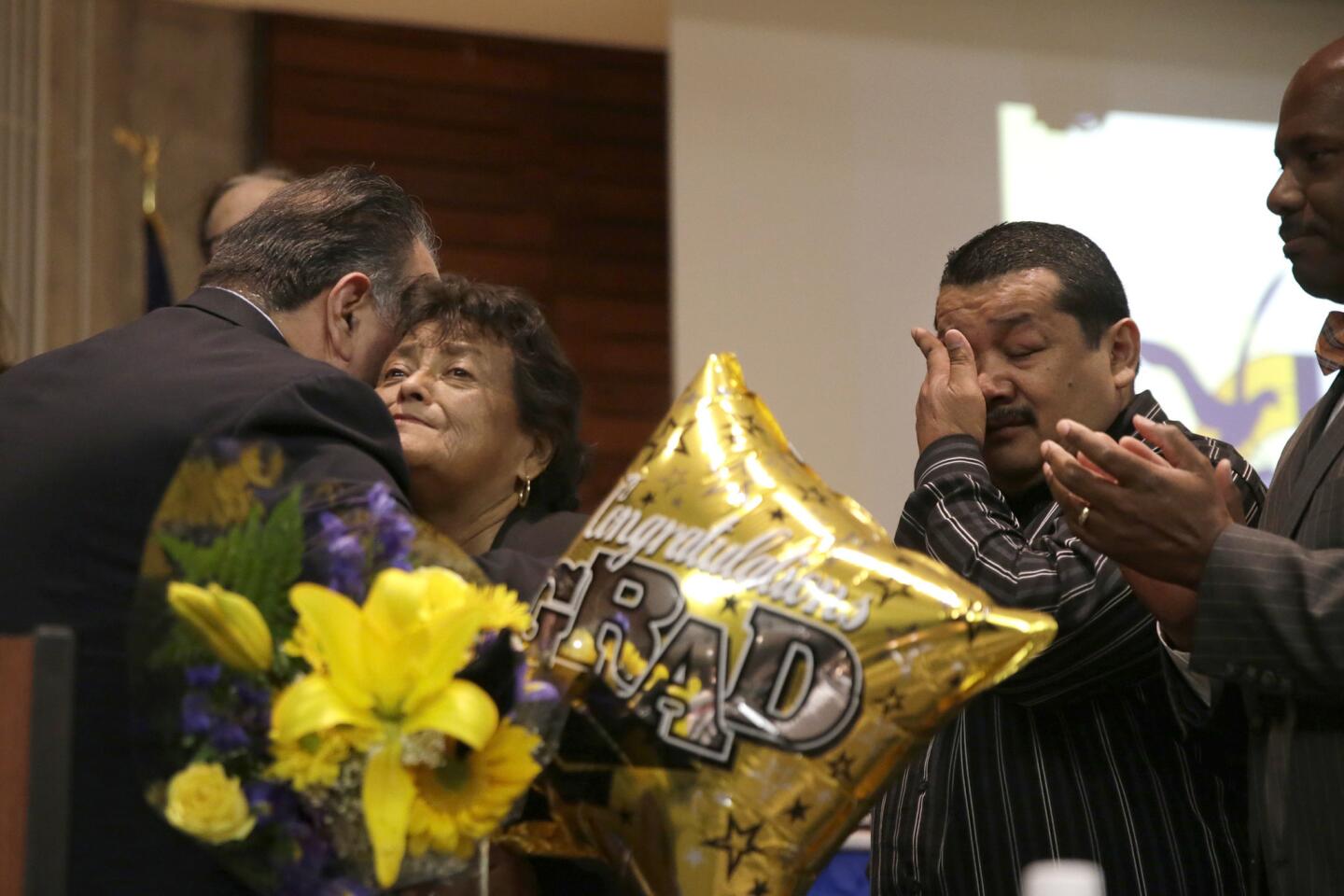 Chancellor Francisco Hernandez comforts Dolores Valles and Juan Manuel Banales, the parents of Aurora Godoy, as Los Angeles Harbor College honors her with a posthumous diploma. Godoy, 26, was the youngest of 14 people killed in the Dec. 2 shooting in San Bernardino.