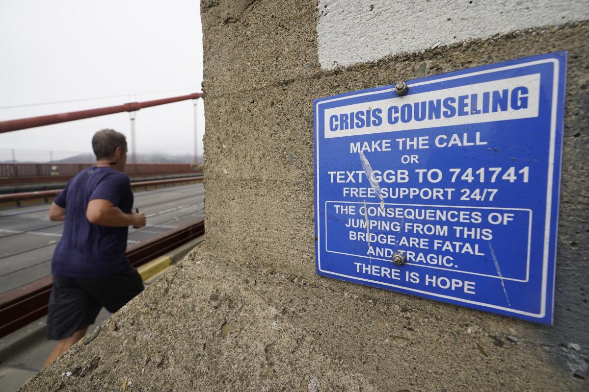 A man jogs past a sign about crisis counseling on the Golden Gate Bridge in San Francisco in 2021. 