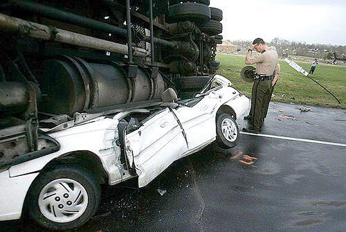 Tennessee Highway Patrolmen look at a car that was crushed beneath a semi-trailer when a tornado hit.