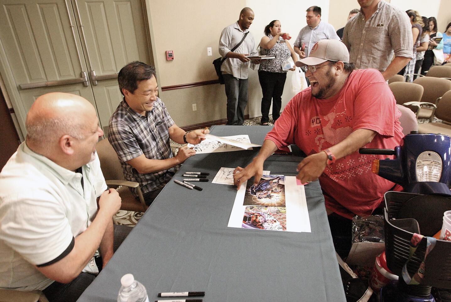 Dan DiDio and Jim Lee sign some artwork for Anthony Ramos of North Hollywood after a presentation about the "essentials" of DC Comics at the Buena Vista branch of the library on Wednesday, August 19, 2015.