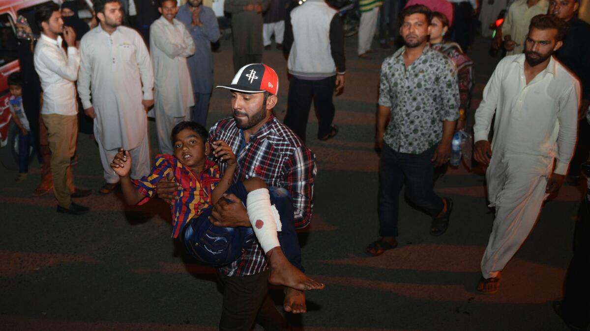 A man carries an injured child to a hospital in Lahore, Pakistan, on Sunday.