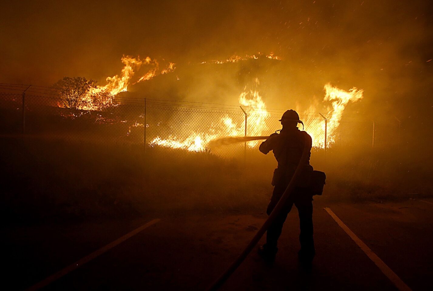 A firefighter battles flames near structures around Sycamore Canyon as the Springs fire makes its way to Pacific Coast Highway.