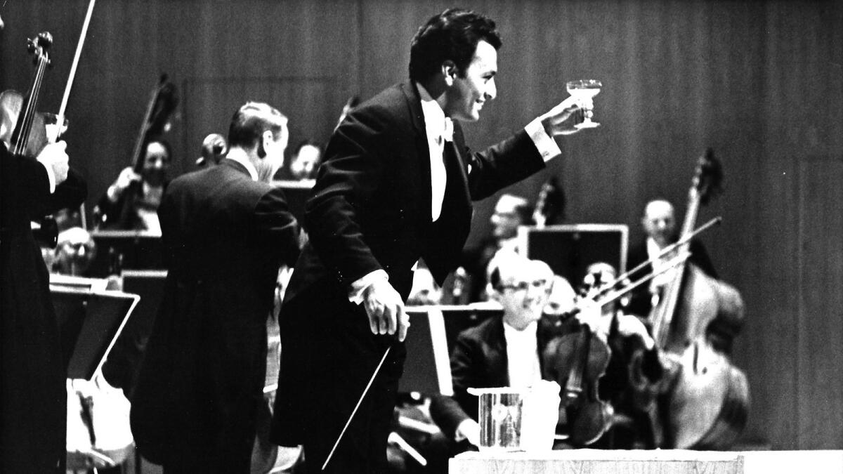 Zubin Mehta enjoys a glass of champagne on stage at the Dorothy Chandler Pavilion at The Music Center on opening night, December 6, 1964.
