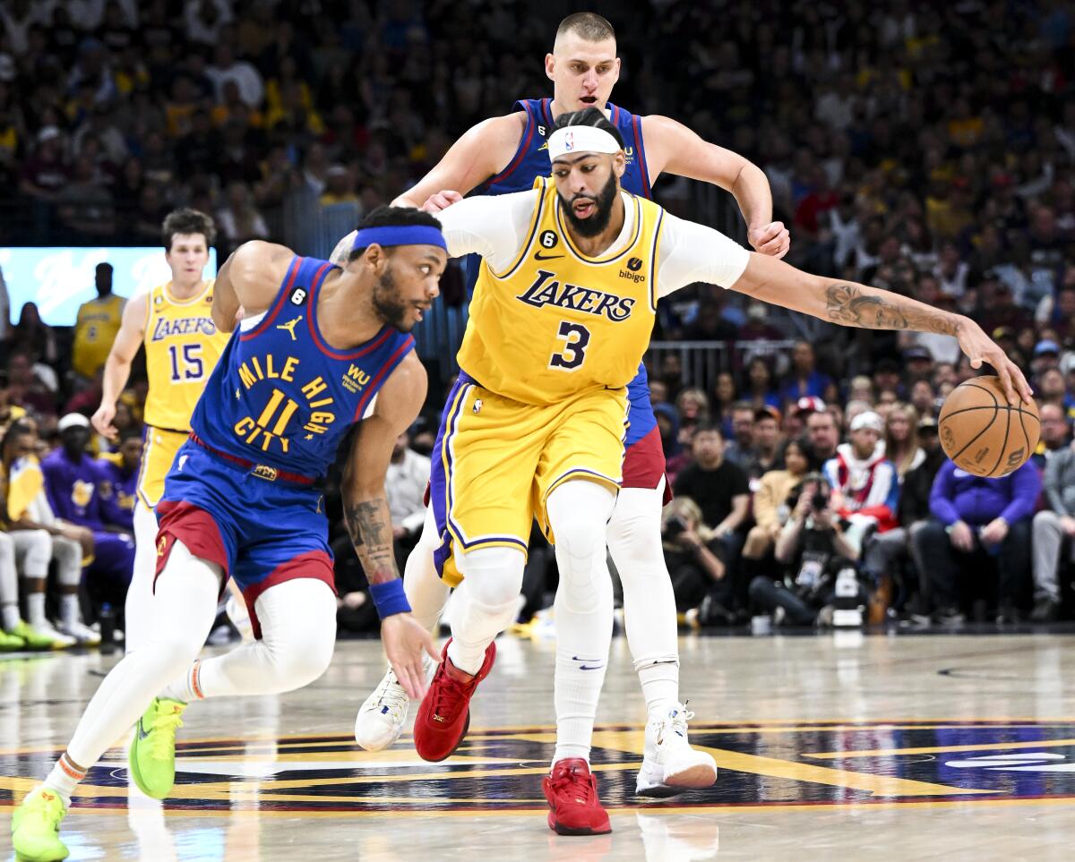 Anthony Davis, center, tries to control the dribble while double-teamed by Denver's Bruce Brown, left, and Nikola Jokic.