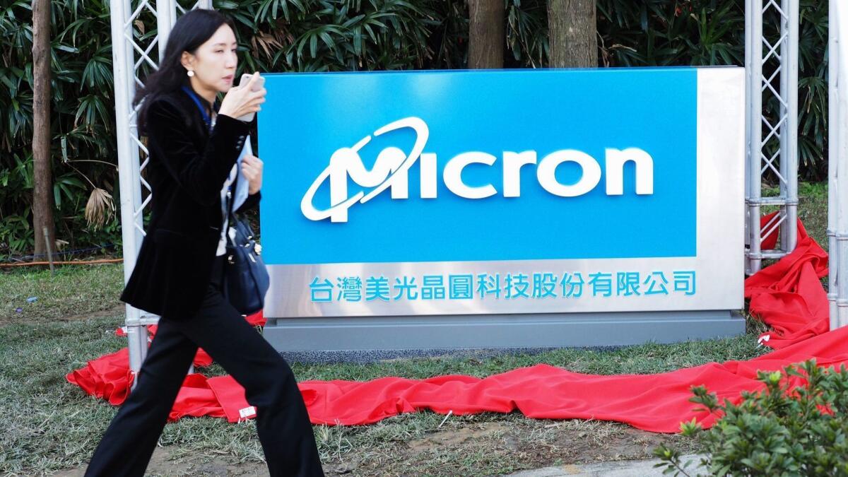 A woman walks past the a Micron Technology sign in Taiwan in 2016. The company said Tuesday that it had started shipping some components to Huawei after its lawyers studied export restrictions.