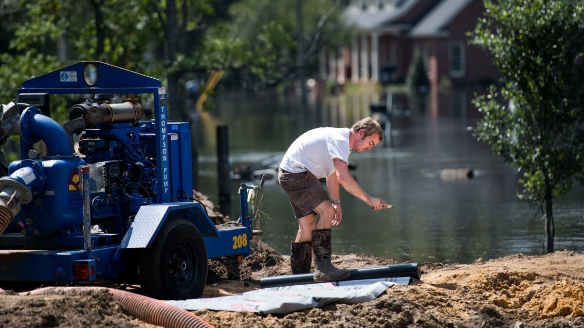 Archie Sanders cuts plastic sheeting while building a temporary levee to hold back floodwaters caused by Hurricane Florence near the Waccamaw River on Sept. 23, 2018, in Conway, S.C.