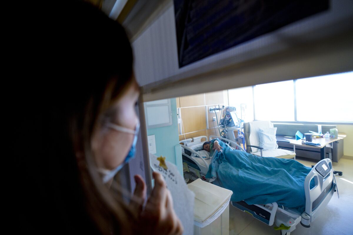 Taylor May from Sharp Memorial Hospital checks on her COVID-19 patient, Cynthia Powers.