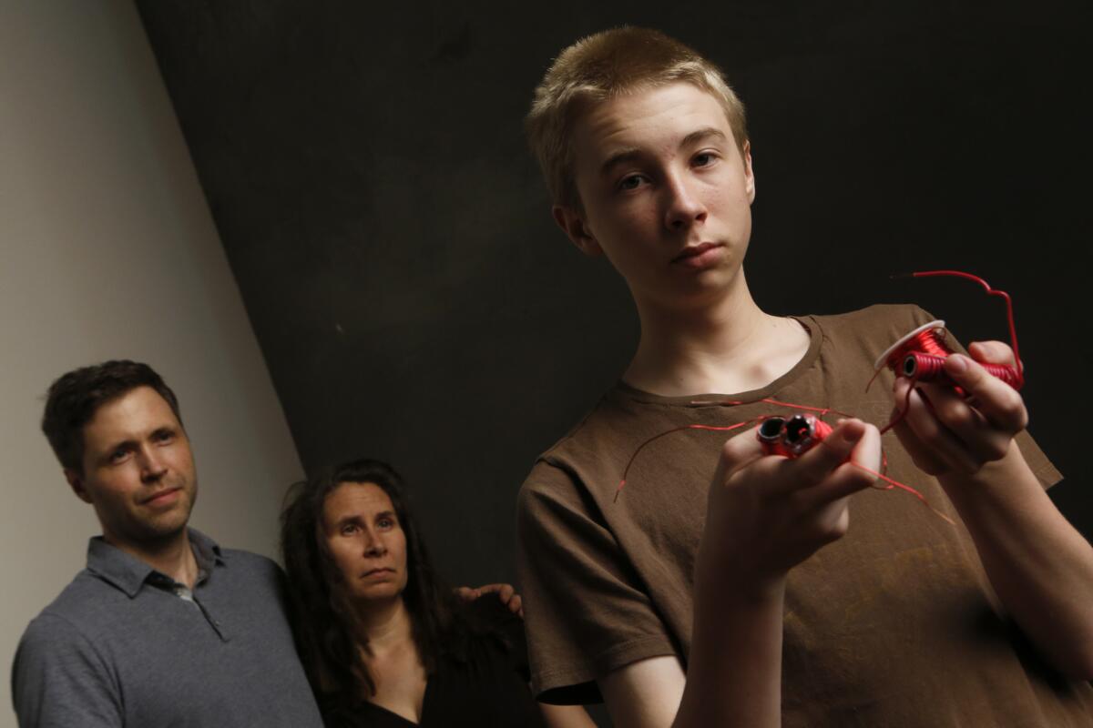 Asa Ferguson, a ninth-grader, holds materials he used for a coil-gun science project, confiscated after administrators decided it was dangerous. His parents, Rogan and Susan Ferguson, stand behind him.
