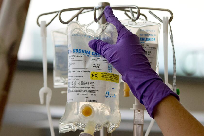 A nurse places a patient's chemotherapy medication on an intravenous stand.