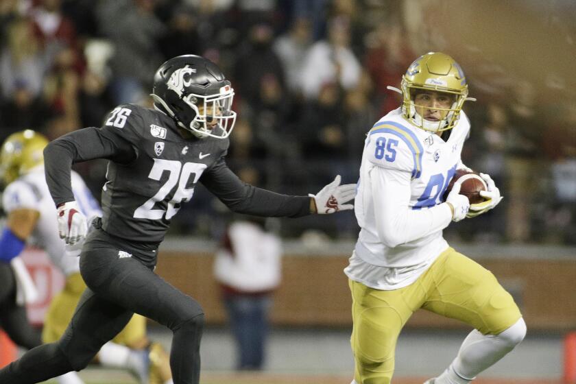 UCLA tight end Greg Dulcich runs with the ball while under pressure by Washington State safety Bryce Beekman.