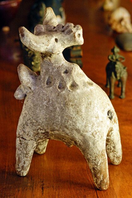 A white-painted terra cotta folk sculpture of Nandi, the bull of the Hindu god Shiva, sits on the living room bookcase.
