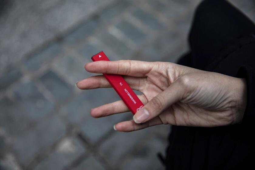 FILE - In this Jan. 31, 2020 file photo a woman holds a Puff Bar flavored disposable vape device in New York. Government researchers reported a big drop in teen vaping this year as many U.S. students were forced to learn from home due to the COVID-19 pandemic. U.S. health officials urged caution in interpreting the numbers Thursday, Sept. 30, 2021, which were collected using an online questionnaire for the first time.(AP Photo/Marshall Ritzel)