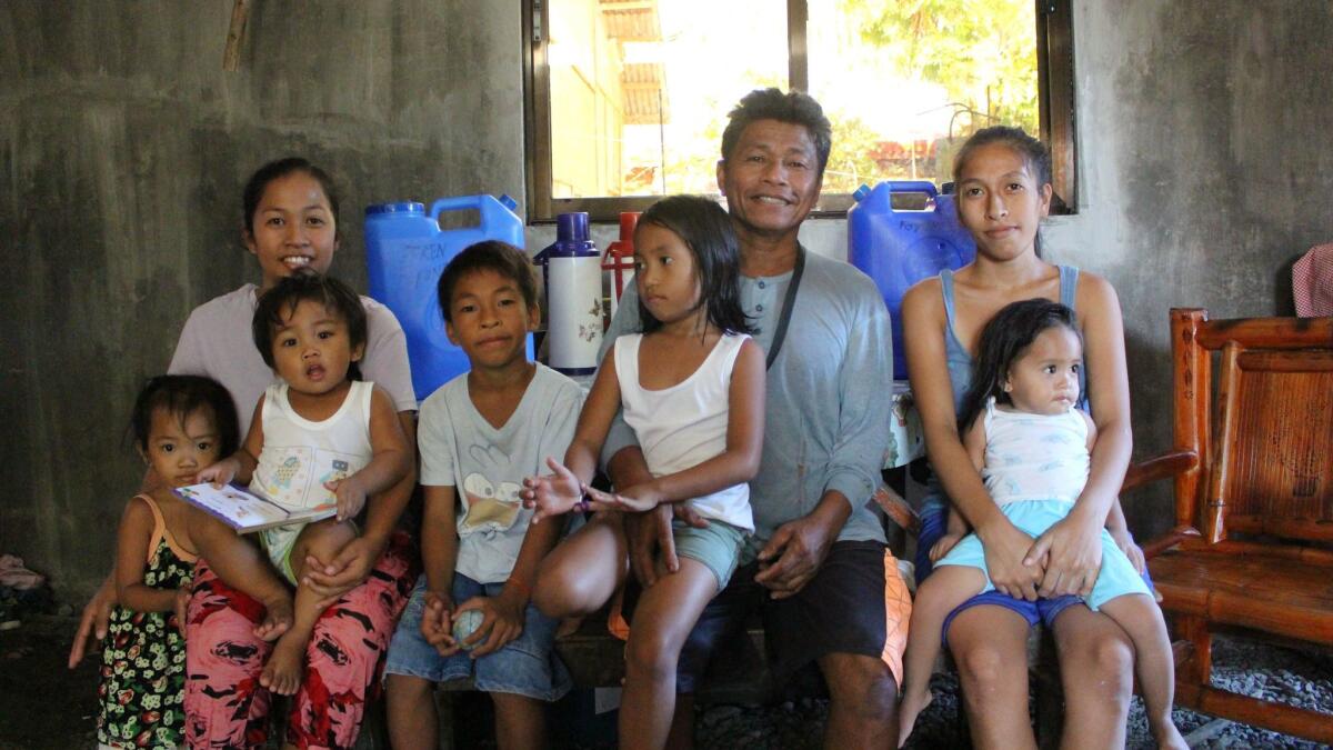 Efren Forones with his family. Left to right: A neighbor's unidentified child; Leah, 25, with her son Jaren, 2, in her lap; Emmanuel, 10; Emmaglyn, 5, on Forones' knee; Sheila, 22, with her daughter, 1-year-old Villagail, in her lap.