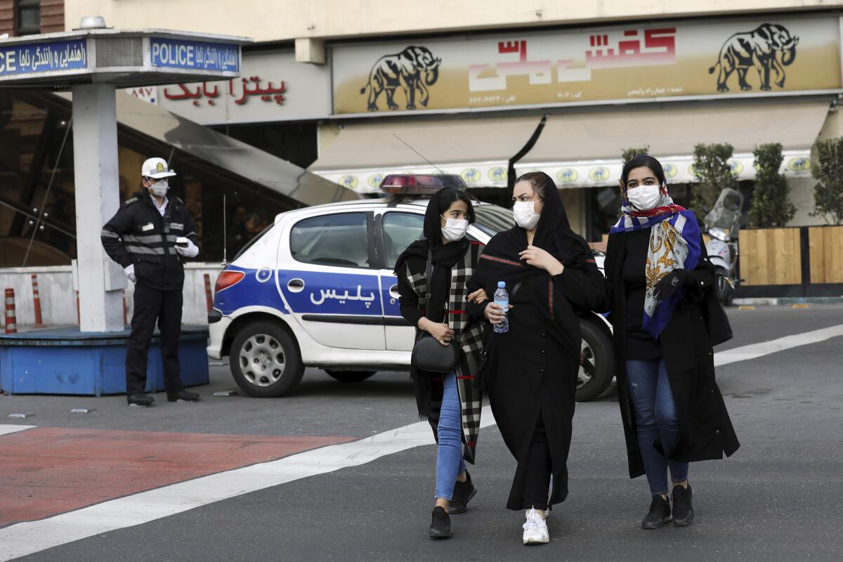 A policeman and pedestrians wear masks to help guard against the coronavirus on Feb. 23 in downtown Tehran.