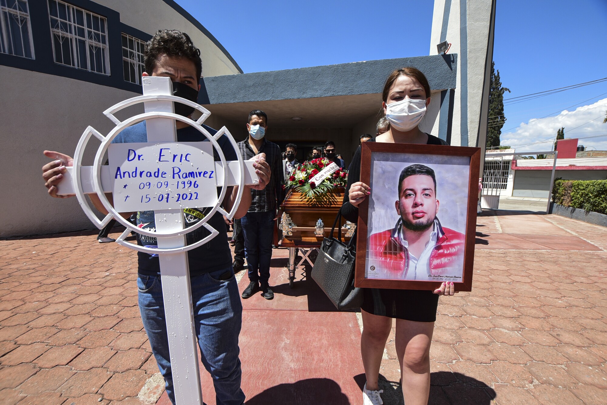 Mourners hold a poster and a portrait. 