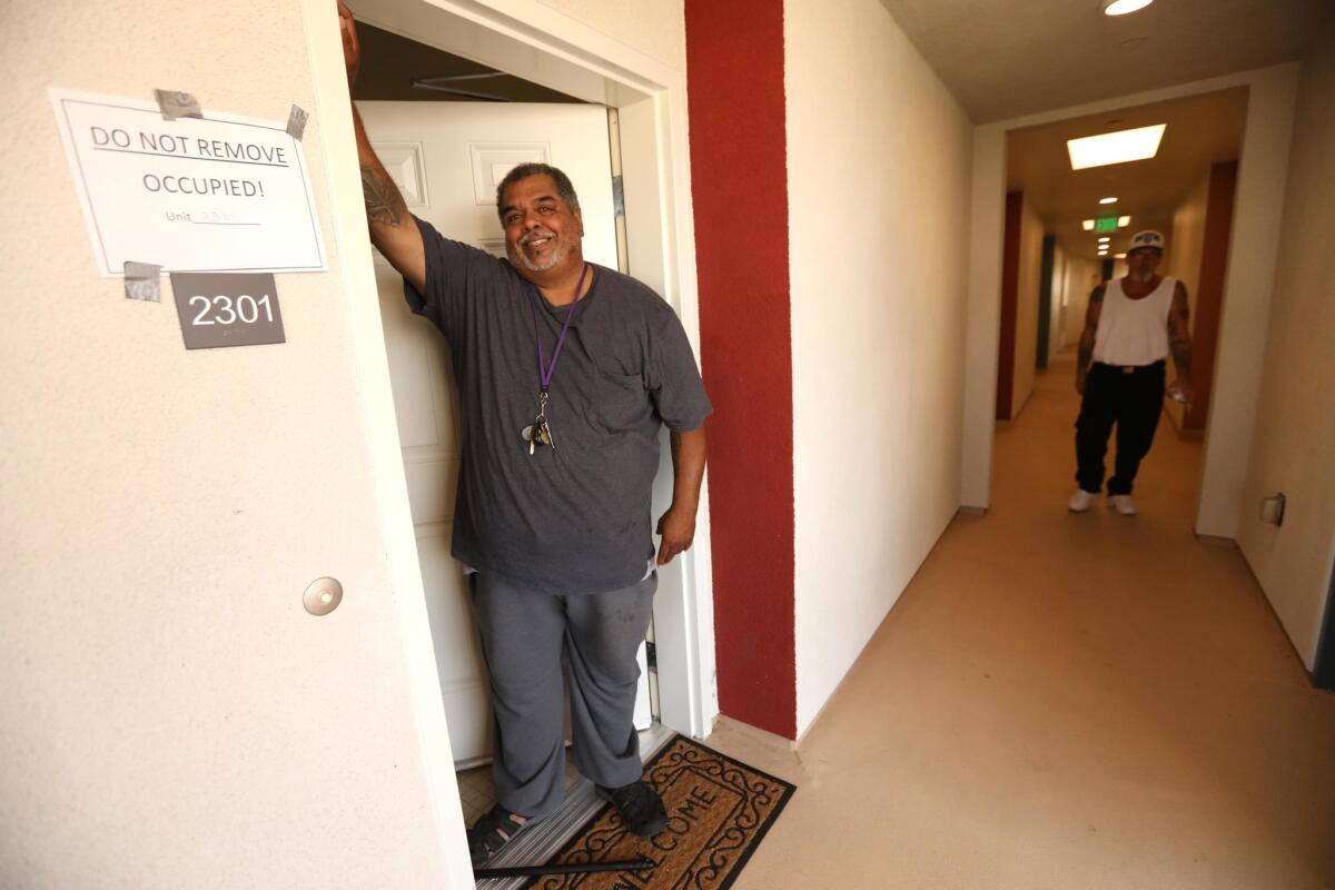 A formerly homeless man stands in the doorway of his new apartment in Bell