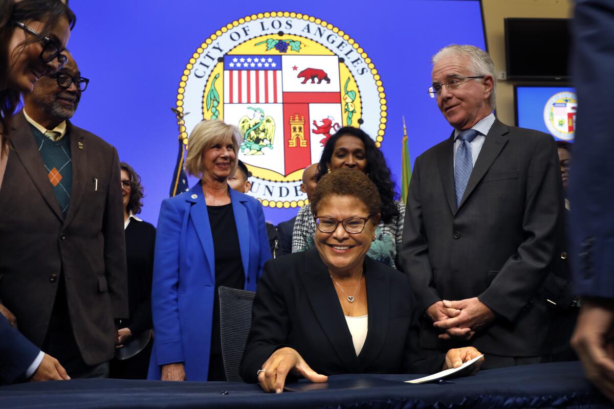Mayor Karen Bass, seated, signs a state of emergency declaration for homelessness in Los Angeles.