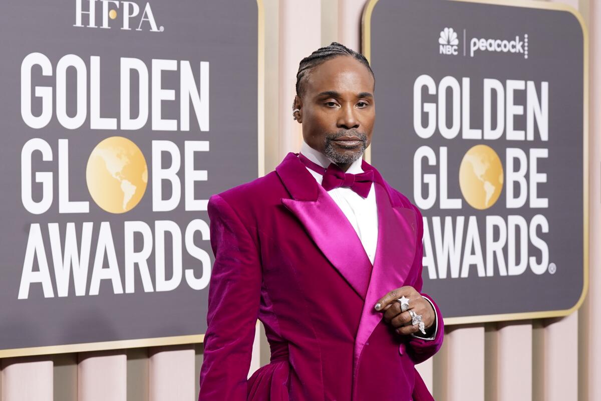 Billy Porter poses for photos at the Golden Globes in a fuchsia suit and bow tie with a white shirt