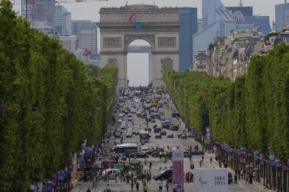 Peatones y vehículos circulan por la avenida Champs Elysees, con el Arco del Triunfo