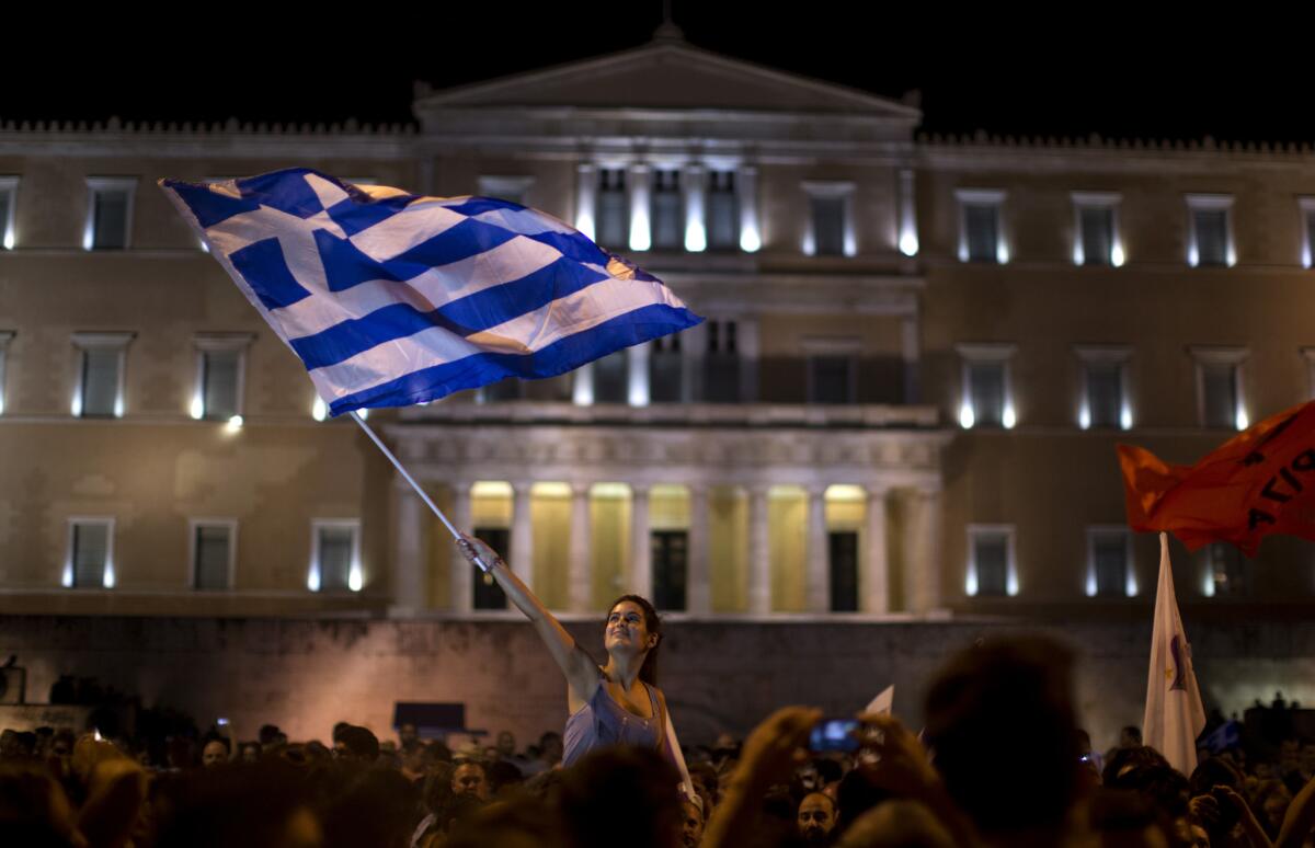 Una mujer ondea una bandera griega durante los festejos tras el triunfo del "No" en el referendo convocado por el gobierno de Grecia, en la Plaza Syntagma frente al Parlamento en Atenas, el domingo 5 de julio de 2015. (Foto AP/Emilio Morenatti)