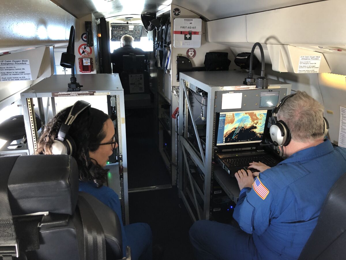 Meteorologists in a jet look at a map showing their path toward an atmospheric river