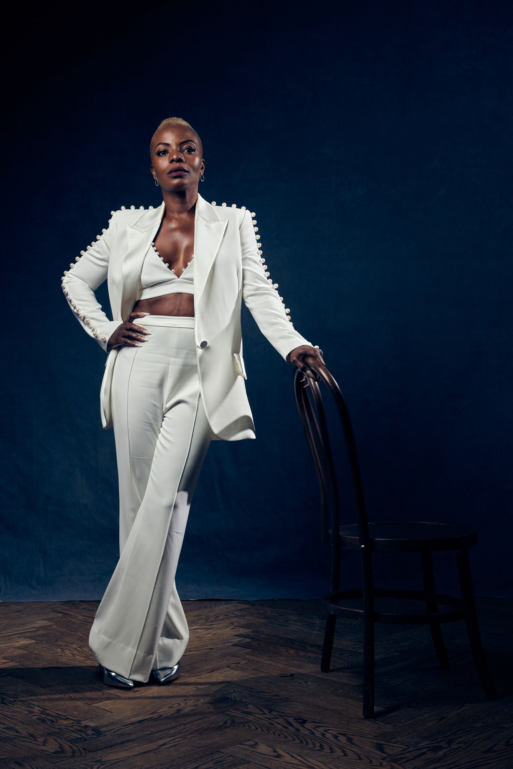 A woman in a white pant suit stands.