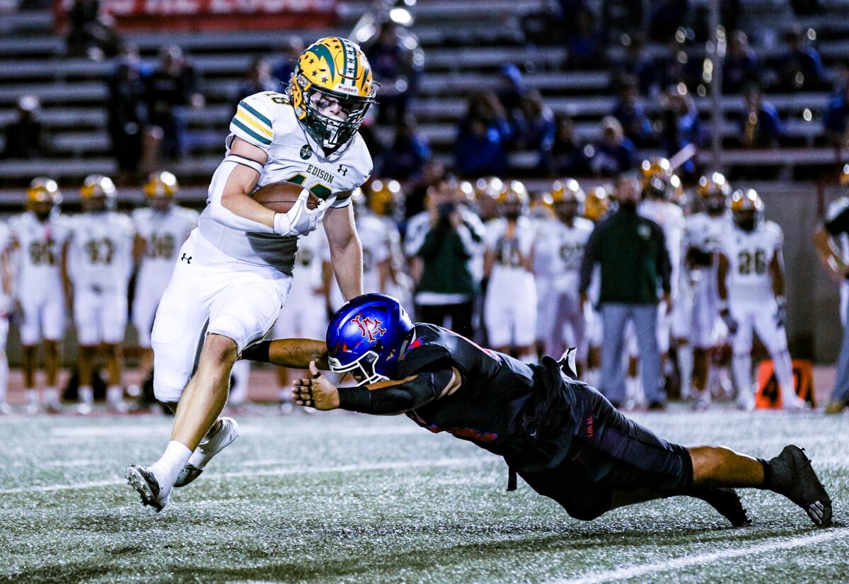 Los Alamitos' Zechariah Misa dives at the legs of Edison's Julius Gillick while trying to make a tackle.