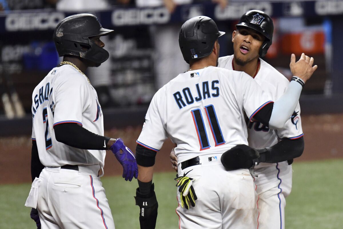 Miami Marlins' Erik Gonzalez, right, and Miguel Rojas (11) celebrate scoring runs during the seventh inning of a baseball game against the Washington Nationals as teammate Jazz Chisholm Jr. (2) looks on, Tuesday, May 17, 2022, in Miami. (AP Photo/Jim Rassol)