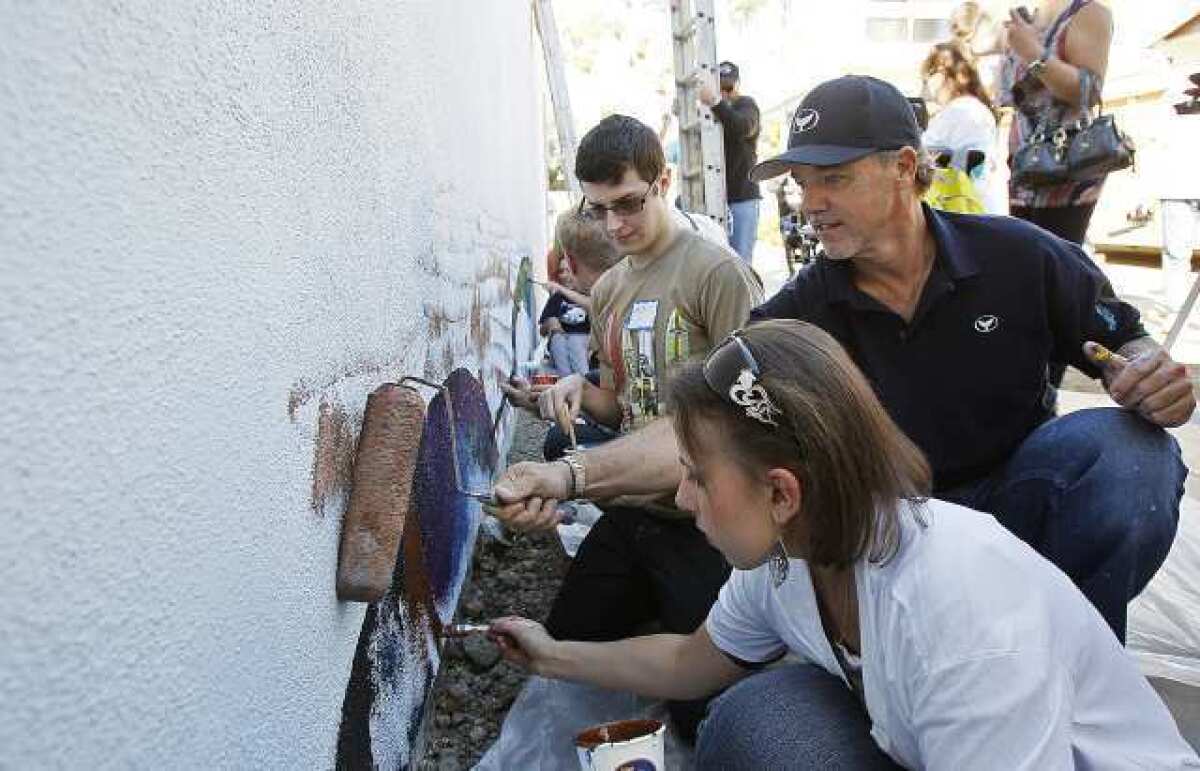 Wyland, center, paints a mural at the Glennwood House of Laguna Beach in 2013.