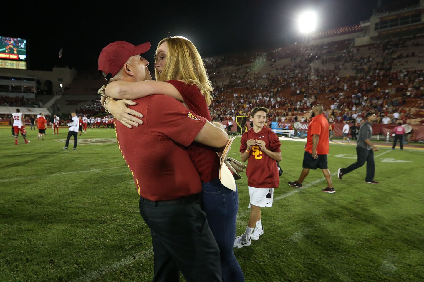 Interim USC coach Clay Helton is embraced by his wife, Angela, at midfield after the Trojans beat Utah 32-24 at the Los Angeles Memorial Coliseum.