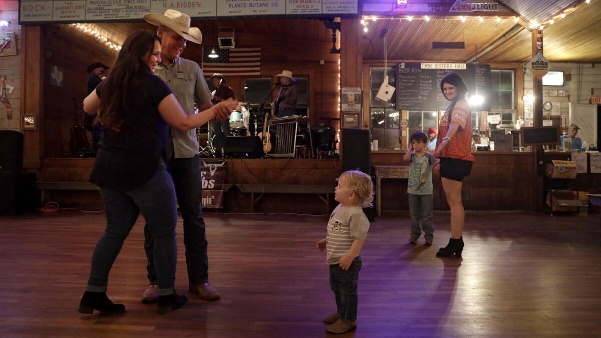 Zane Casey, 2, watches grandparents Bill and Michelle Boop, left, do the two-step as the Caliche Crossroads band plays at Twin Sisters Dance Hall in Blanco, Texas on a Saturday night. At right is his mother, Kayla Casey, and older brother, Zander, 6.