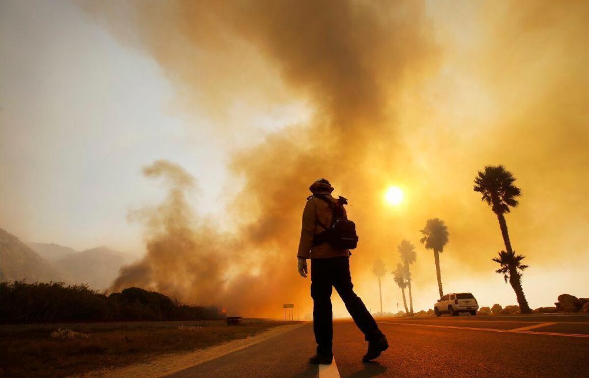 A firefighter monitors the Thomas fire burning alongside the 101 Freeway on Dec. 7, 2017.
