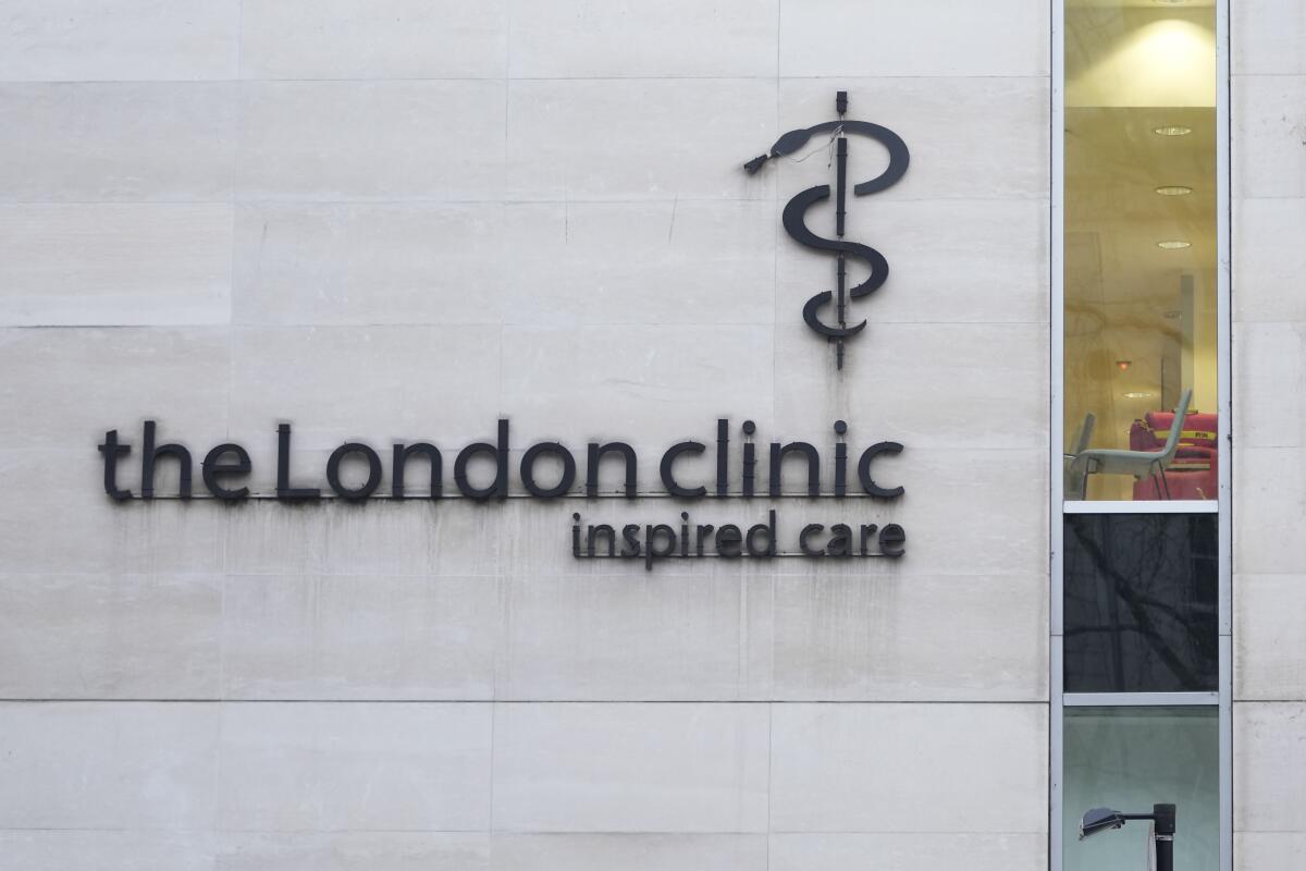A black logo on light stone wall reads 'the London clinic, inspired care' underneath a modified cadeuceus