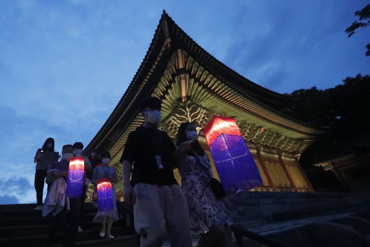 Visitors holding Korean traditional lanterns walk around during the Moonlight Tour at Changdeokgung Palace in Seoul, South Korea, Thursday, Aug. 13, 2020. The palace reopened Thursday after having been closed for two months due to the coronavirus pandemic. (AP Photo/Ahn Young-joon)