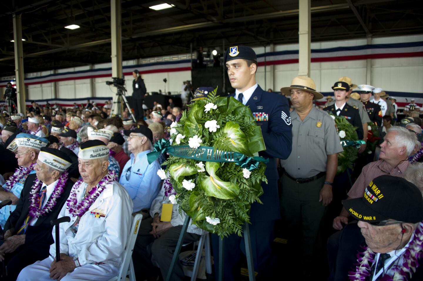 Air Force Staff Sergeant Mose Matila stands at a wreath as Ranger Joseph Borja stands behind him during a wreath laying ceremony to commemorate 75th anniversary of the attack on Pearl Harbor in Honolulu.