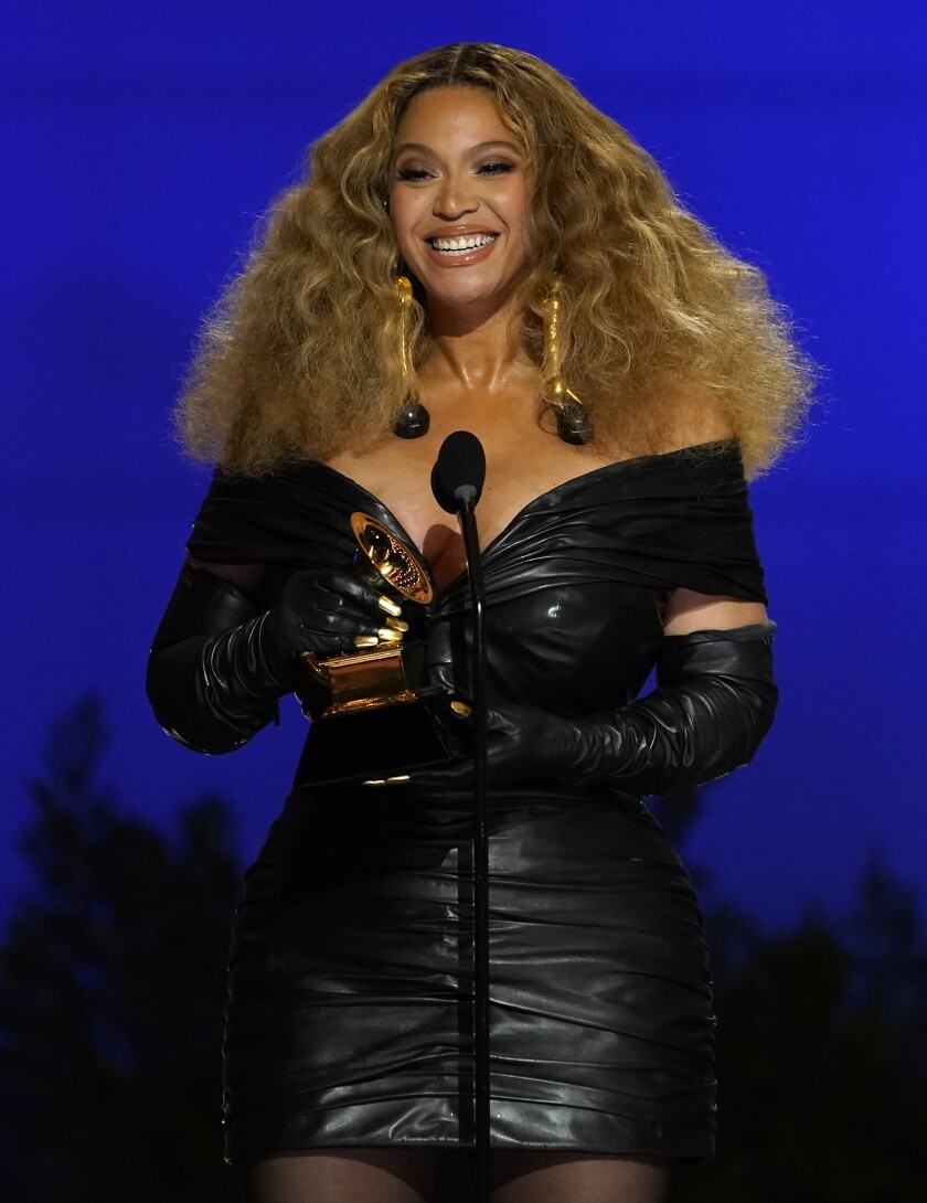 A woman in a black dress and gloves accepts a music award onstage