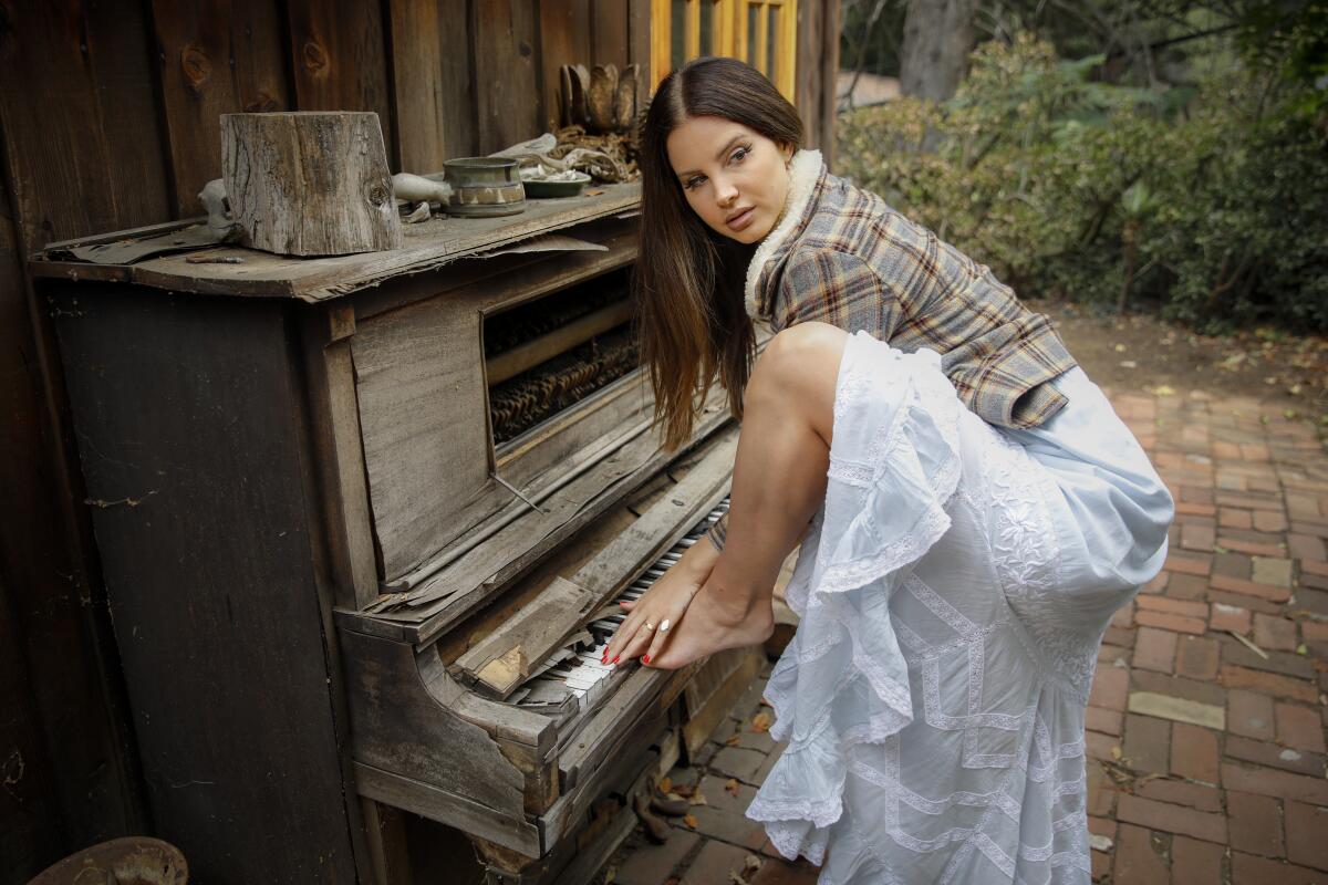 Lana Del Rey poses with a broken-down piano