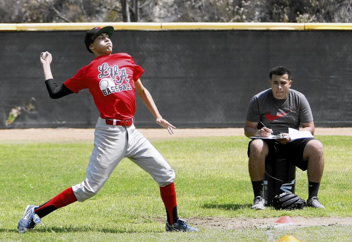 Edward Lopez, 14 of Los Angeles, shows how far he can throw the ball during U.S. Baseball Academy camp at Glendale Sports Complex in Glendale on Tuesday, June 24, 2014.