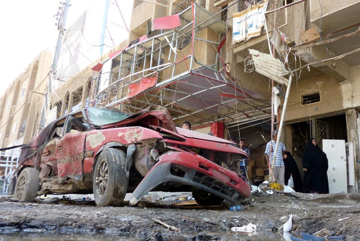 Iraqis survey the damage at the scene of a car bomb attack in the Shaab neighborhood of northern Baghdad.