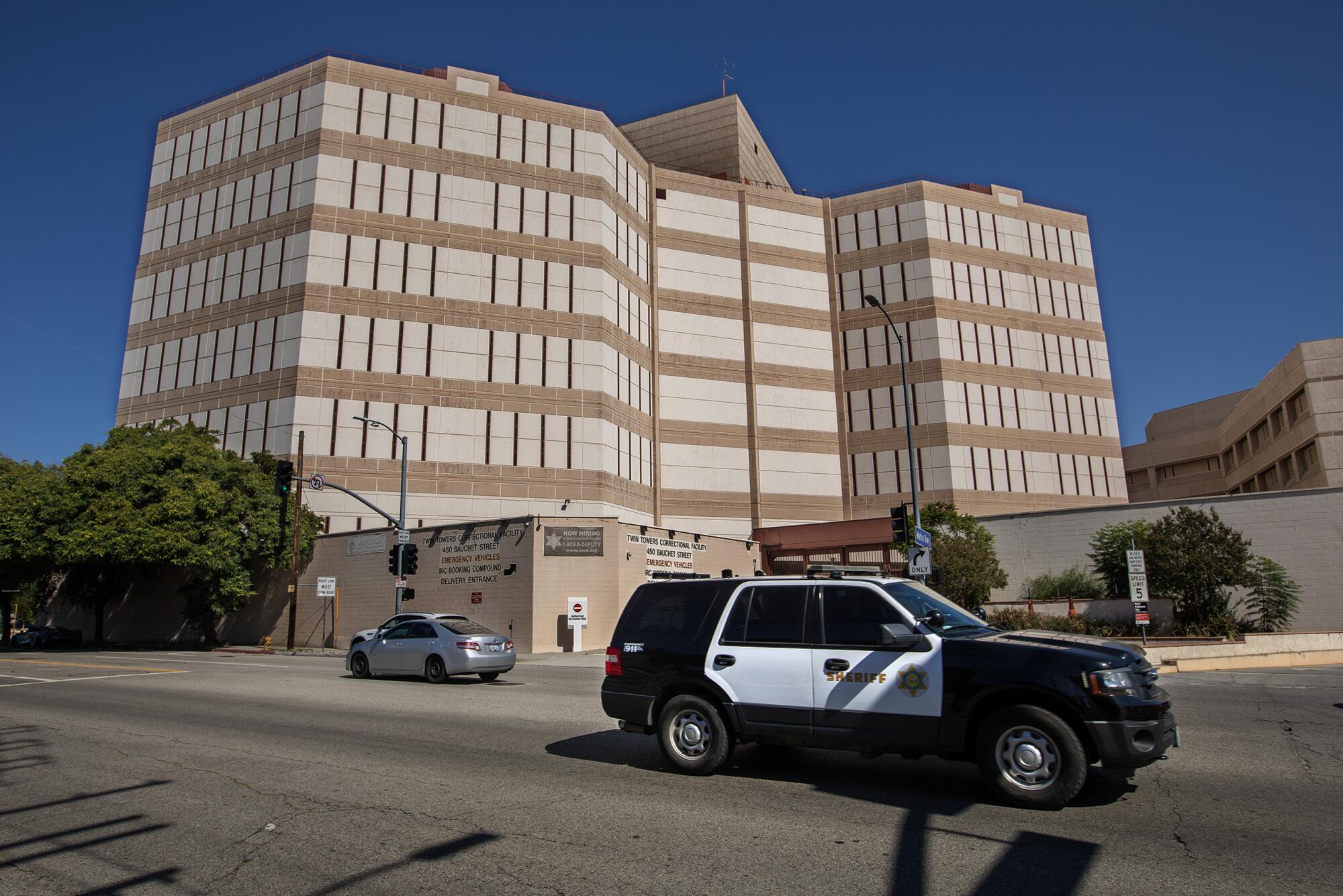 A police SUV passes in front of a building.