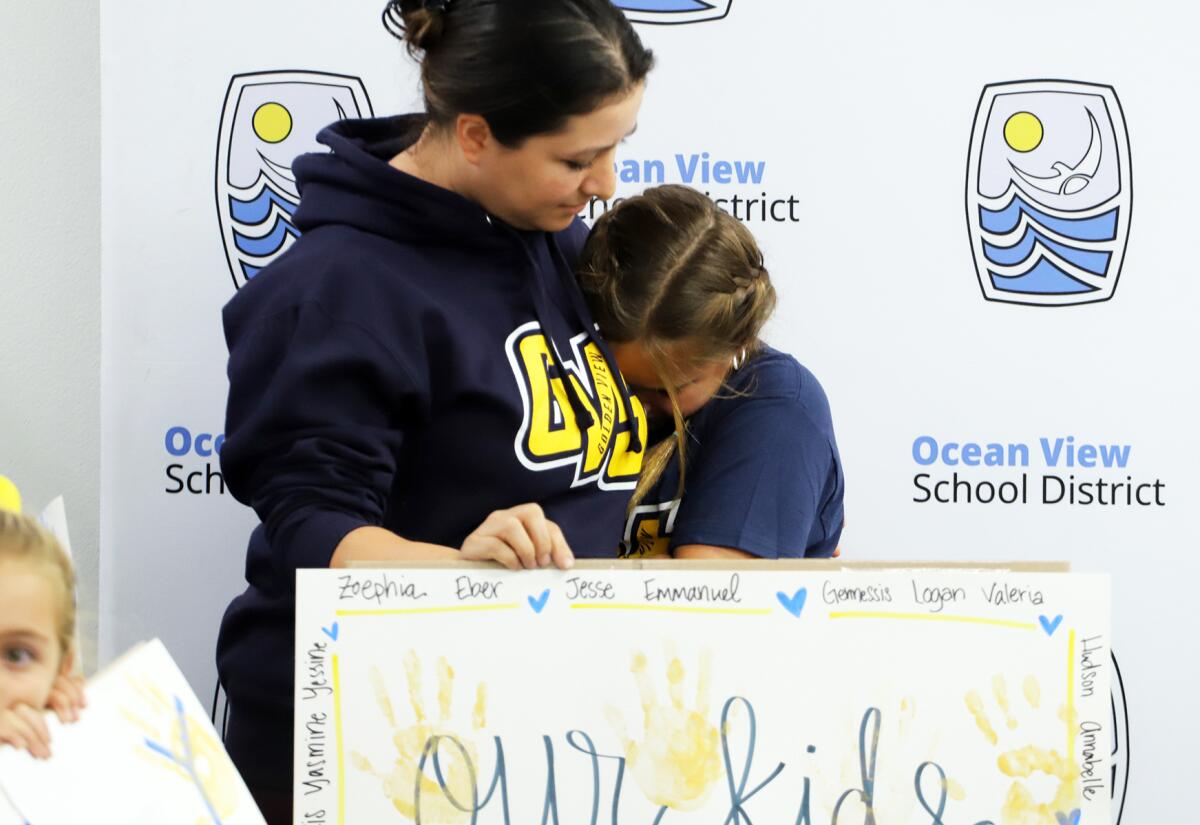 A student from Golden View Elementary hugs her mother during Tuesday's meeting.