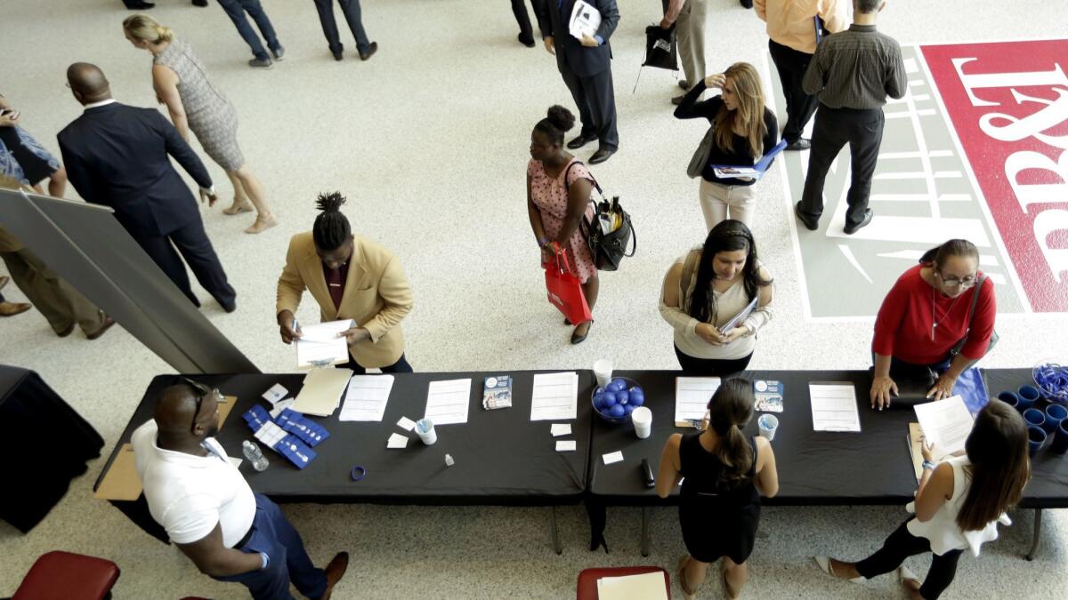 Job applicants talk with potential employers at a job fair earlier this year in South Florida.