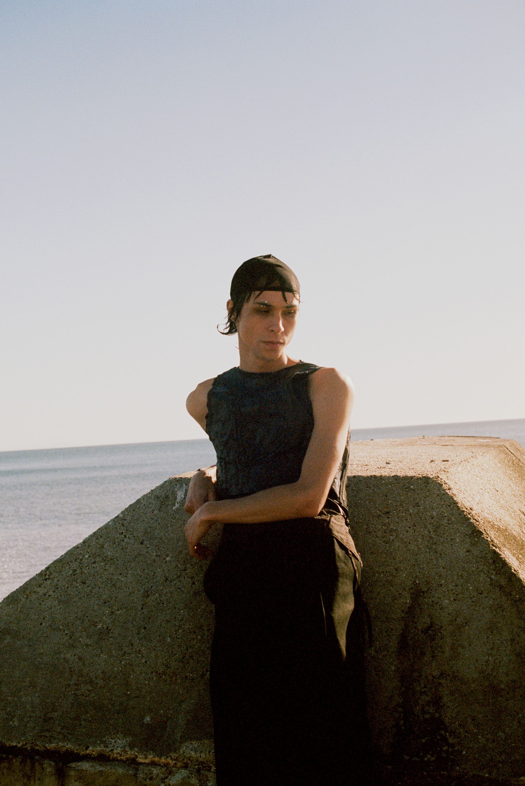 The detox for L.A. life you deserve is an all-black wardrobe A model in a black tank top leans against a concrete slab on the beach.