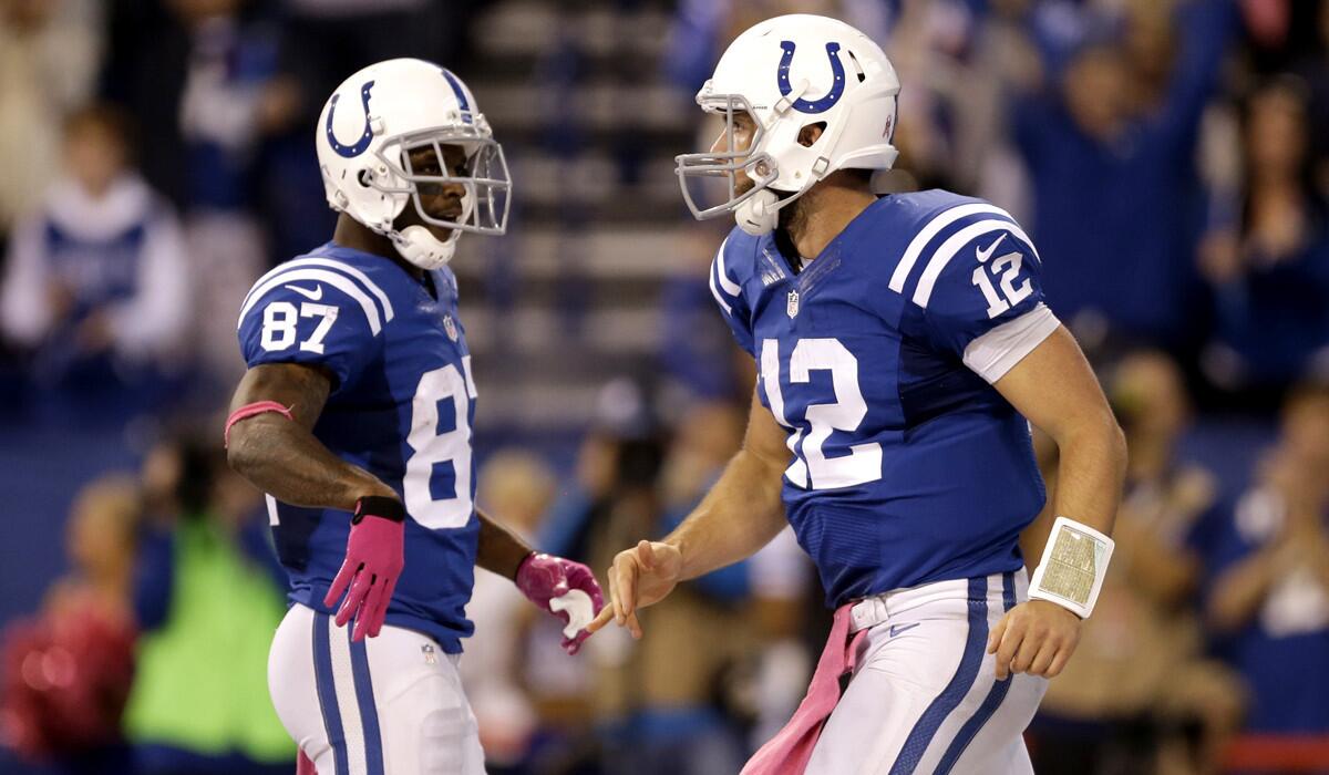 Colts quarterback Andrew Luck (12) celebrates with wide receiver Reggie Wayne after scoring on a run against the Ravens last week in Indianapolis.