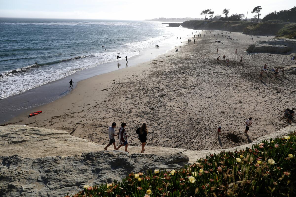 Beachgoers trek across Lighthouse Field State Beach in Santa Cruz.